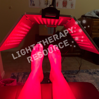 Person receiving red light therapy under a flip panel device labeled 'Light Therapy Resource'.