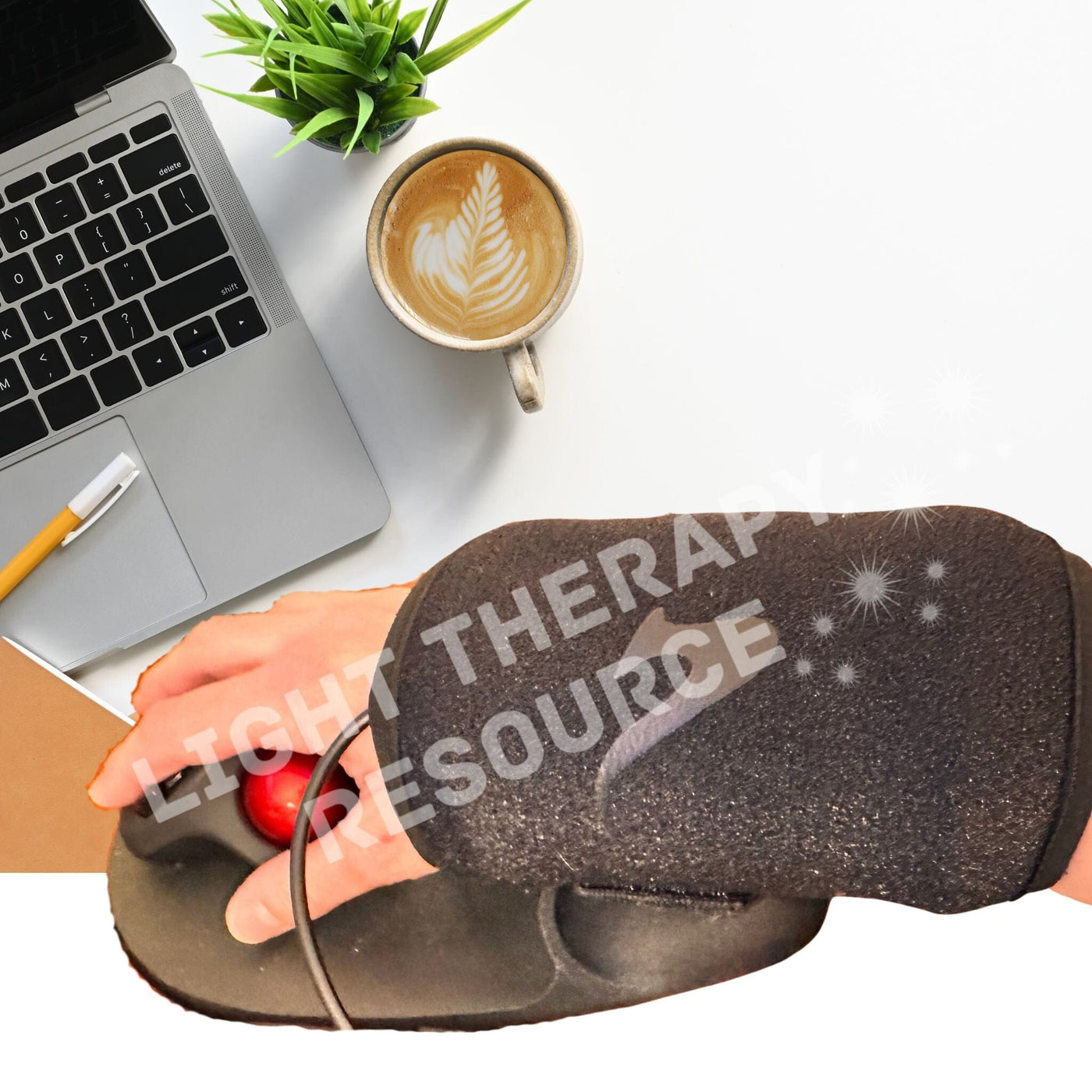 Hand wearing a red light therapy glove with 'Light Therapy Resource' text, laptop, and coffee on a desk.