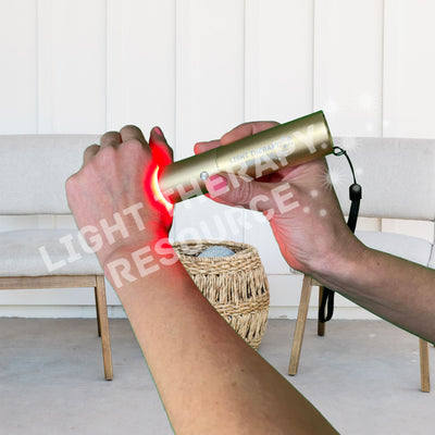 A person holding a red light therapy torch against their hand, near the thumb, with text overlay 'Light Therapy Resource" on a white background.