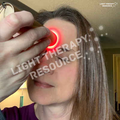 A woman using a red light therapy torch on their face at Yin-Tang between the eyes with 'Light Therapy Resource' text overlay.